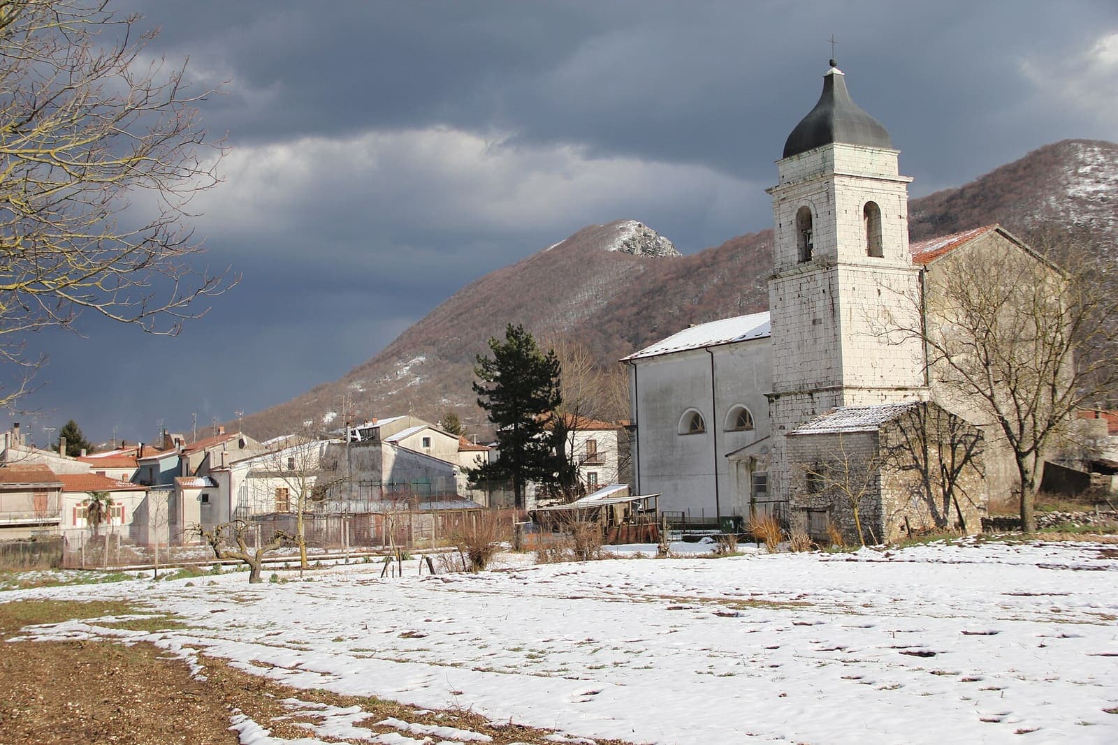 La chiesa di Conca Casale con il campanile, tra la neve e le montagne