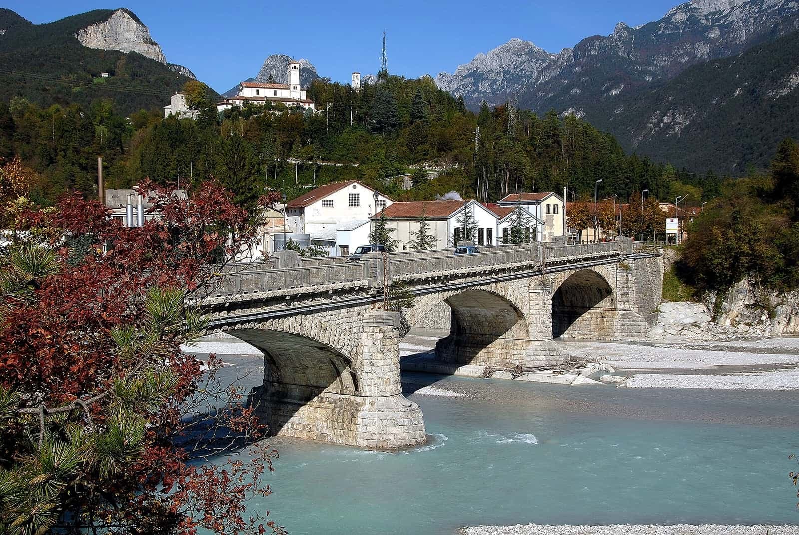 Il ponte sul fiume Fella a Moggio Udinese, con l'abbazia di San Gallo sul colle e le montagne