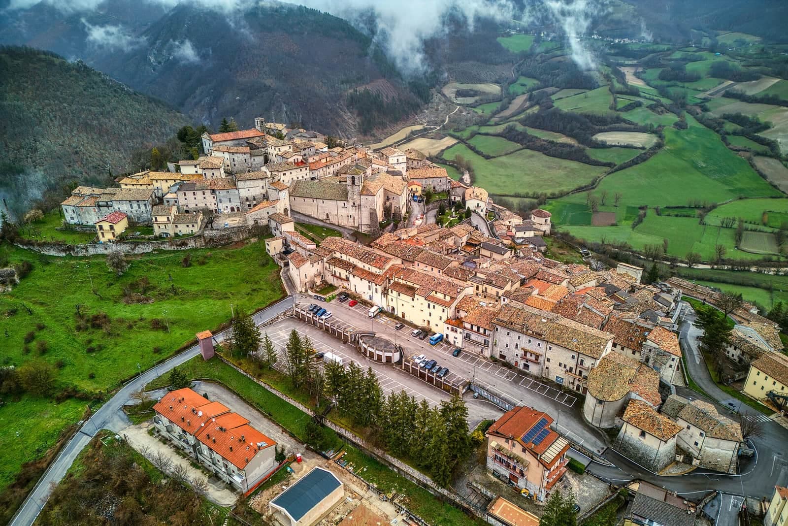 Monteleone di Spoleto vista dall'alto, con le case tra i prati e i monti