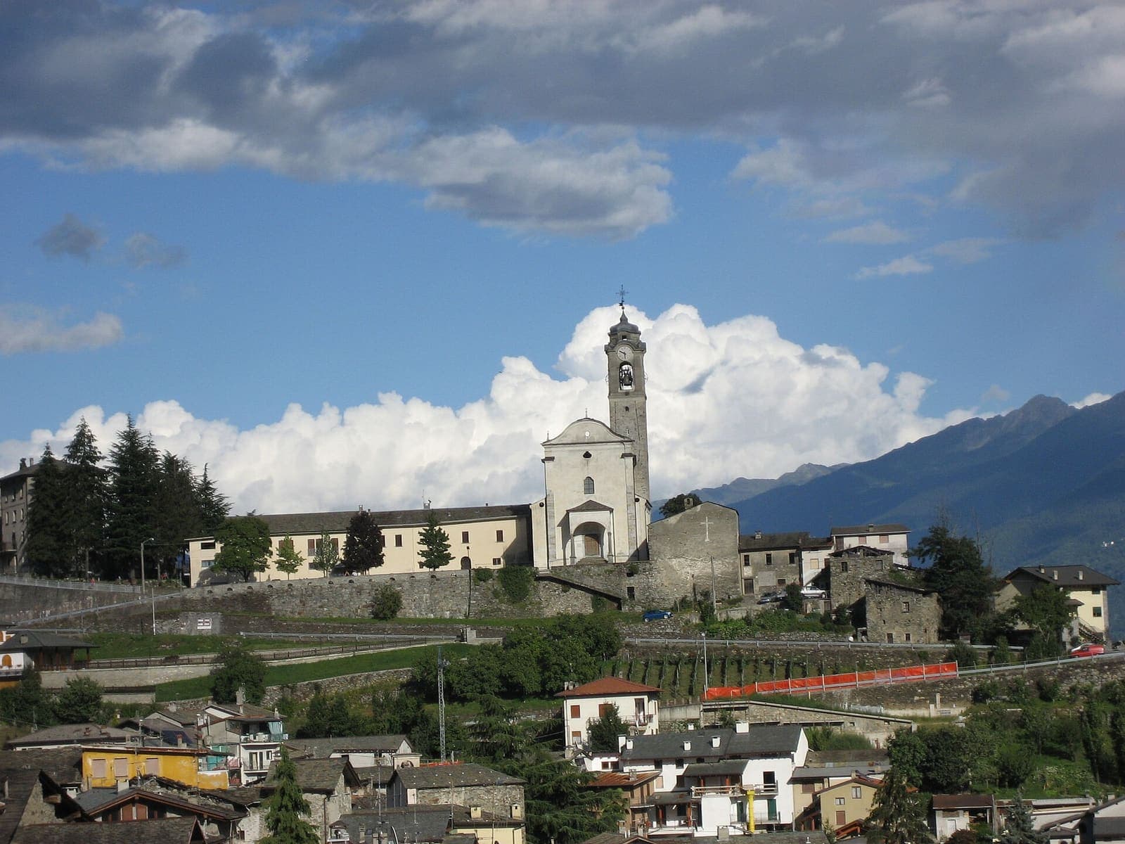 Panorama di Poggiridenti con la chiesa di San Fedele e le montagne sullo sfondo