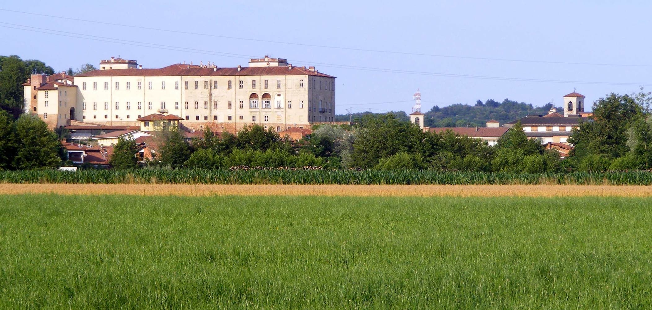 Il castello e il campanile di San Giorgio Canavese oltre i campi verdi