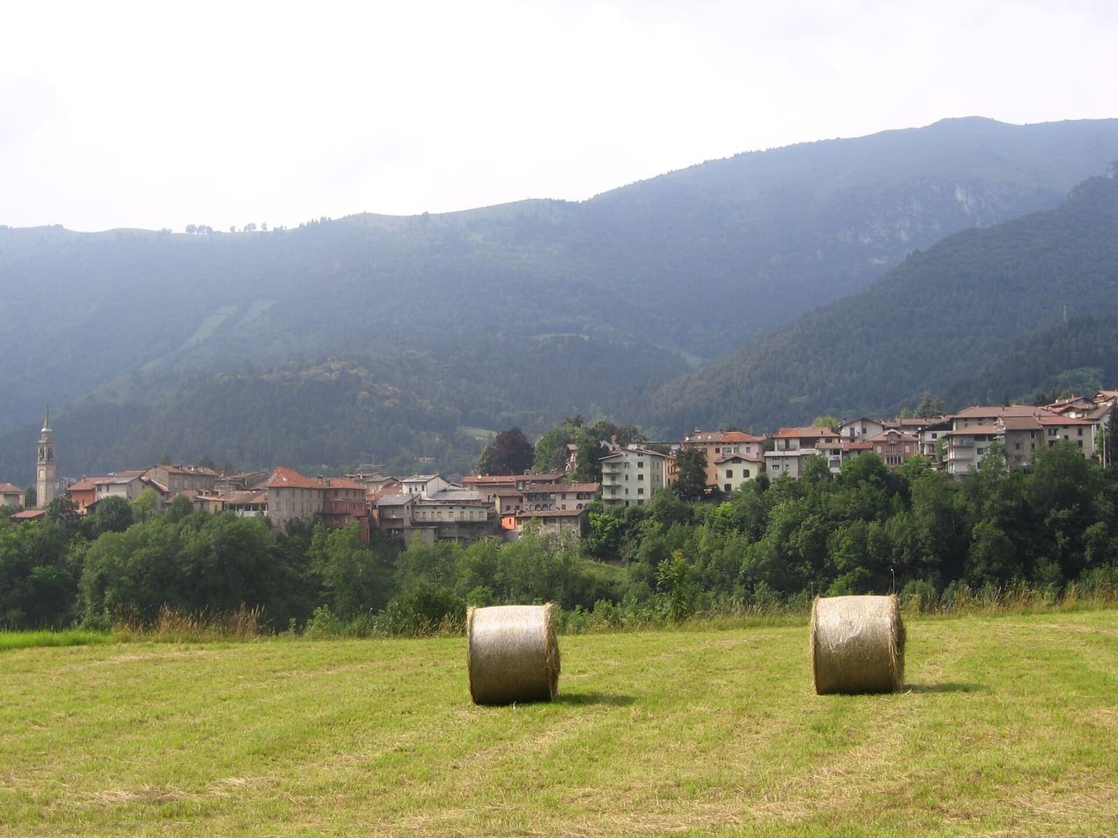 Fino del Monte oltre il prato con le balle di fieno, ai piedi dei monti