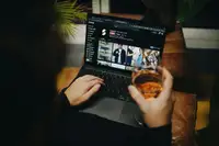 Persona rilassata sul divano di casa con un laptop