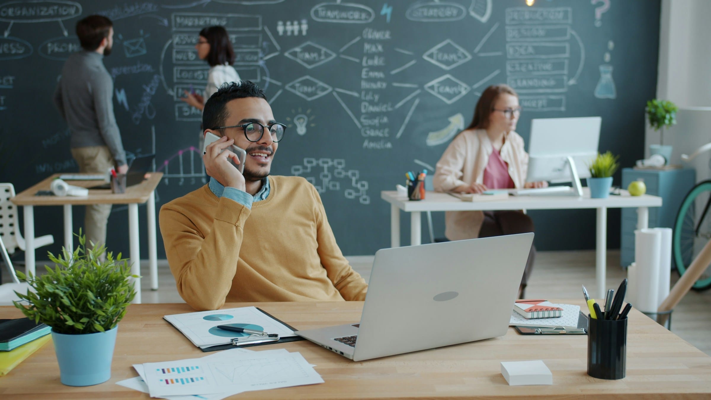 Professionista al telefono in un ufficio moderno con il team di lavoro