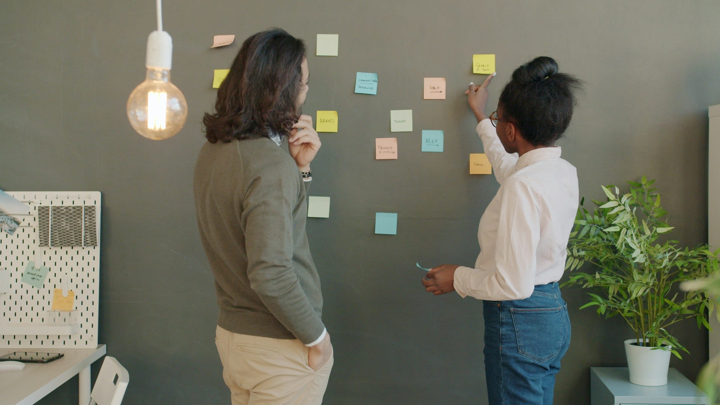 Due persone fanno brainstorming davanti a una parete con post-it