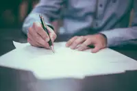 Persona che rivede e firma un documento con una penna