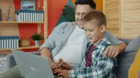 Padre e figlio guardano insieme lo schermo di un laptop