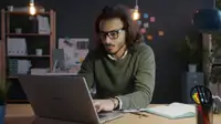 Persona concentrata al laptop in ufficio in penombra