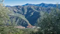 Borgo italiano arroccato tra colline verdi e montagne