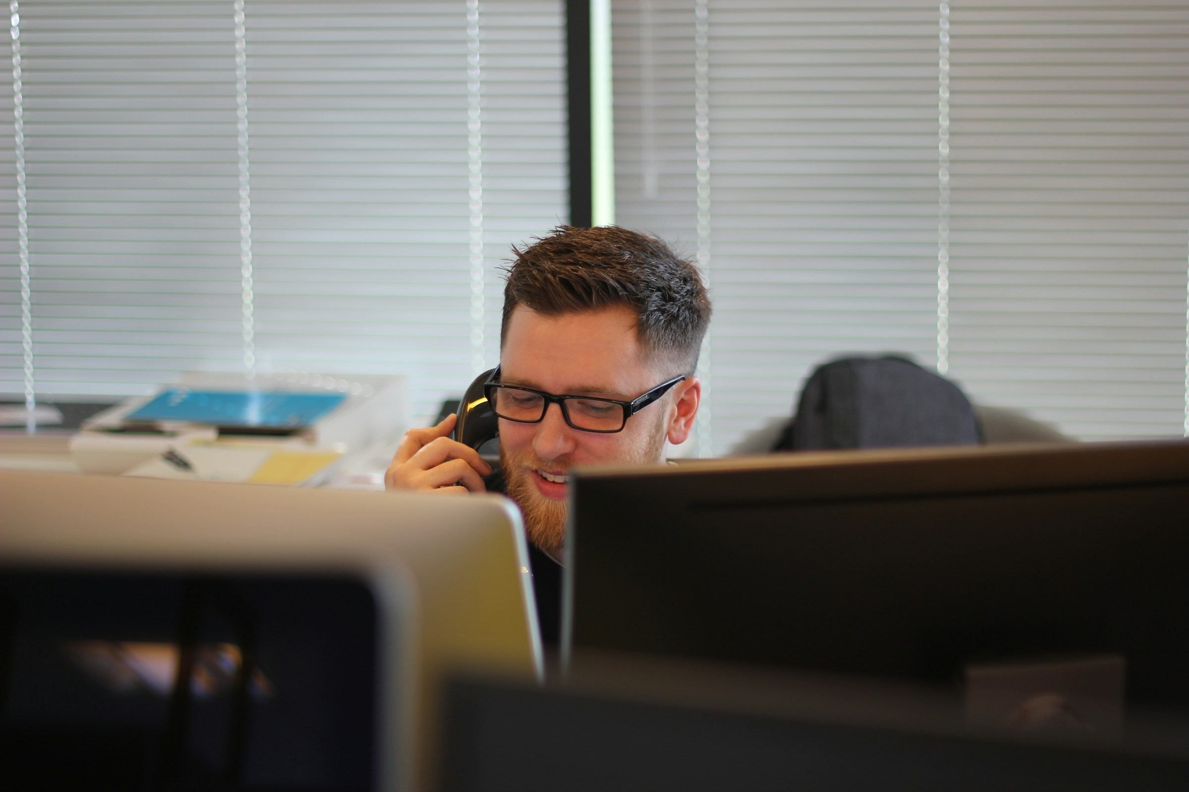 Persona in ufficio al telefono fisso durante una chiamata VoIP